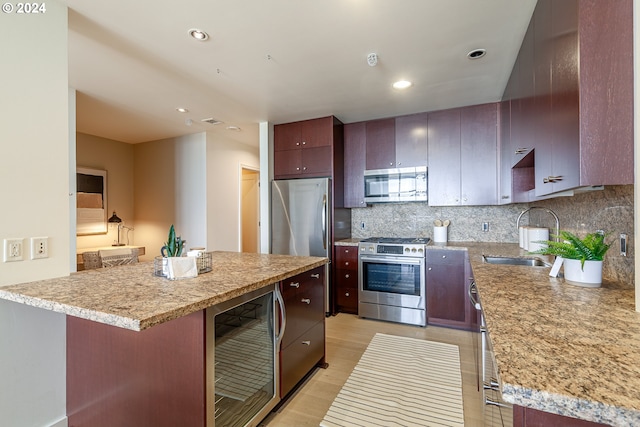 kitchen featuring a center island, sink, tasteful backsplash, stainless steel appliances, and beverage cooler