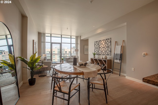 1025 NW Couch St Unit 1020, Portland, OR 97209 - dining area featuring light wood-style floors, baseboards, and a wall of windows