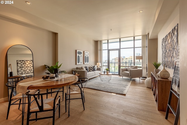 dining space with a wall of windows and light hardwood / wood-style flooring