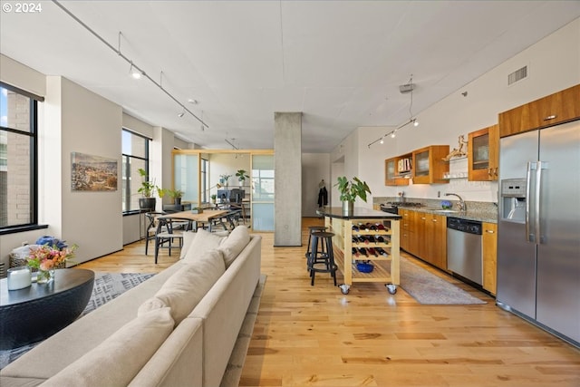 kitchen with rail lighting, sink, a breakfast bar area, stainless steel appliances, and light wood-type flooring