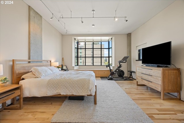 bedroom with track lighting and light wood-type flooring