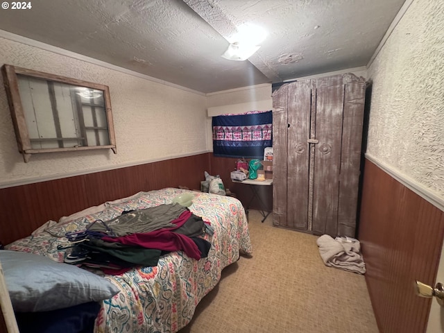 bedroom with crown molding, wooden walls, light colored carpet, and a textured ceiling