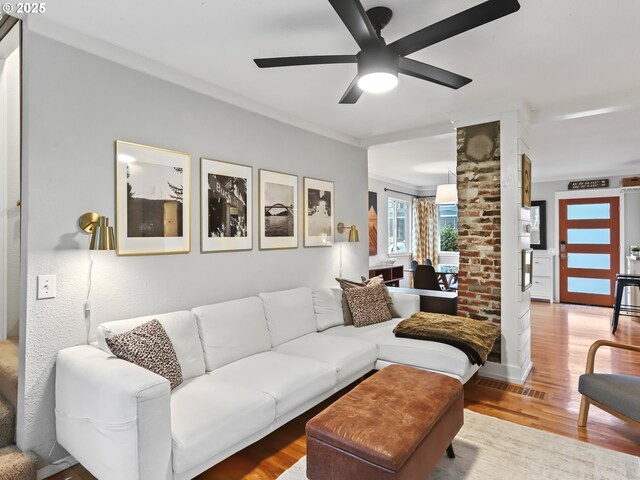 living room with hardwood / wood-style flooring, ceiling fan, and ornamental molding