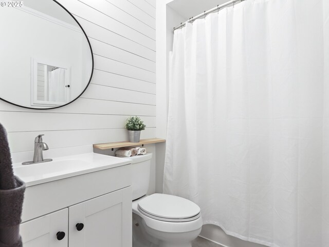 bathroom featuring wood walls, vanity, and toilet