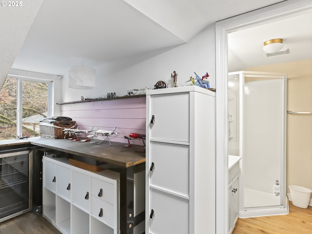 kitchen with hardwood / wood-style floors, white cabinets, beverage cooler, and vaulted ceiling