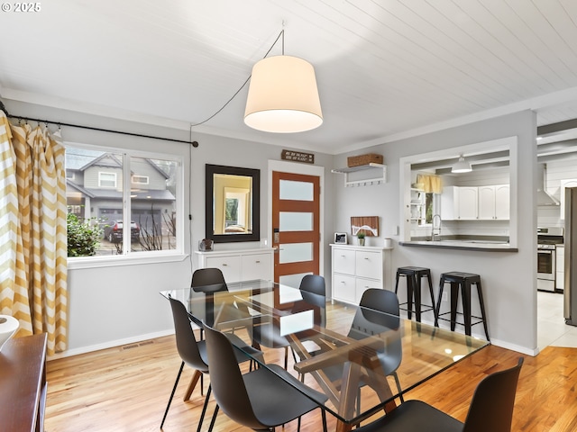 dining space with sink, light wood-type flooring, ornamental molding, and wooden ceiling