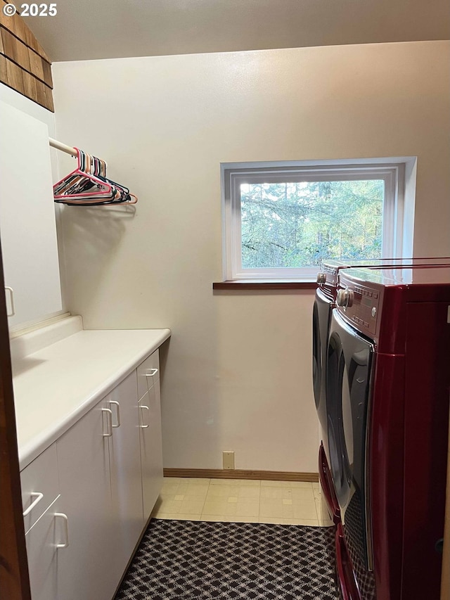 clothes washing area with washer and dryer, cabinets, and light tile patterned flooring