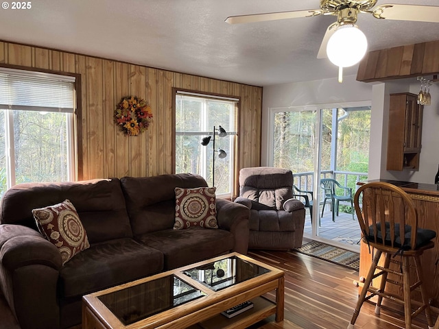 living room featuring ceiling fan, wood-type flooring, and wood walls