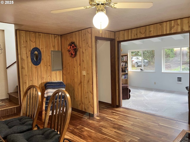 carpeted dining space with ceiling fan and wooden walls