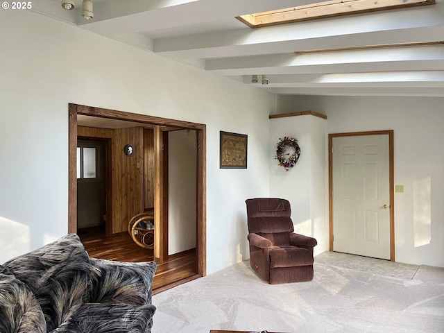 living area with light carpet, beam ceiling, a skylight, and wooden walls