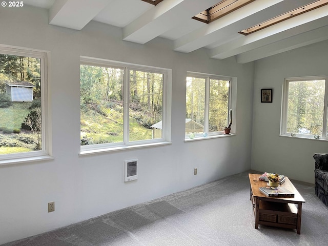 interior space featuring beam ceiling, a skylight, and carpet floors