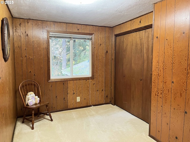 carpeted empty room featuring a textured ceiling and wood walls