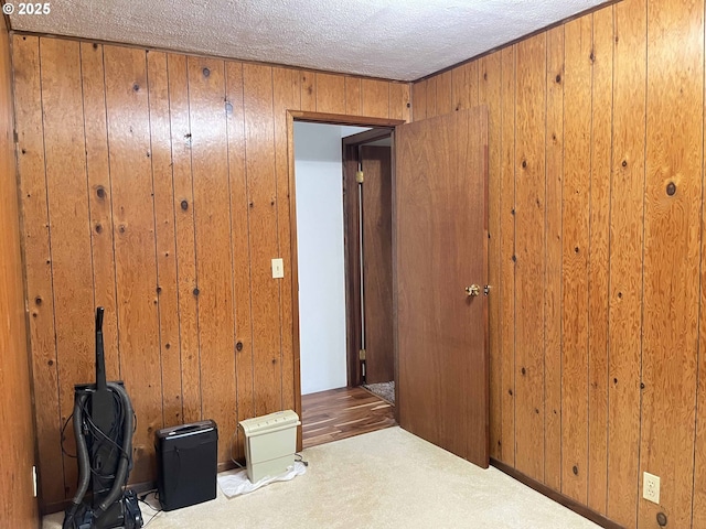 bedroom with carpet, wood walls, and a textured ceiling