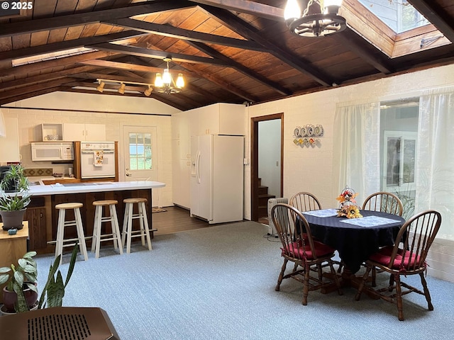 dining area featuring vaulted ceiling with skylight, a notable chandelier, and wooden ceiling