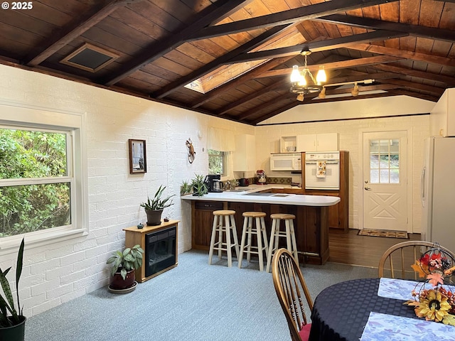 dining space featuring vaulted ceiling with skylight, a notable chandelier, carpet flooring, wood ceiling, and brick wall