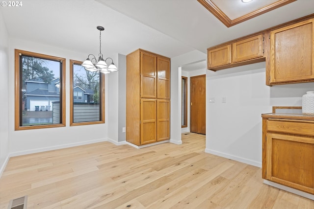 kitchen featuring crown molding, pendant lighting, light hardwood / wood-style flooring, and a notable chandelier