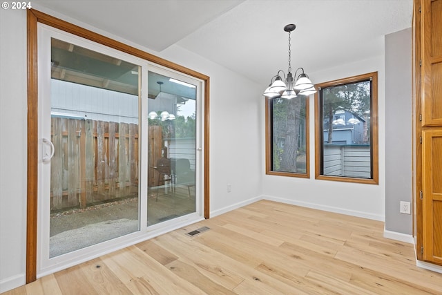 unfurnished dining area with light wood-type flooring and a notable chandelier