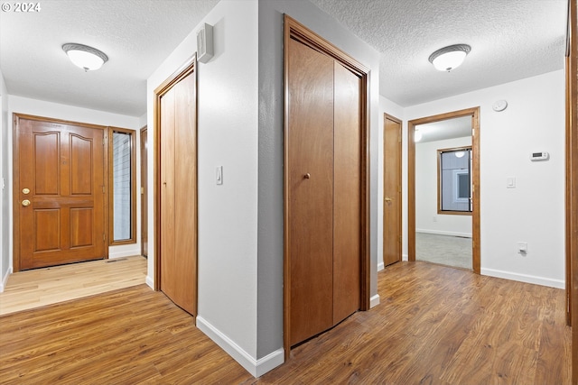 corridor with a textured ceiling and light wood-type flooring