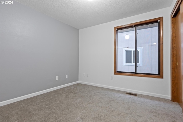 carpeted spare room with a textured ceiling