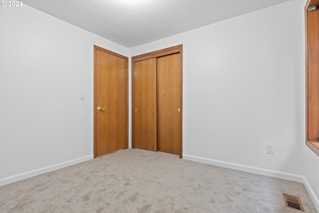 unfurnished bedroom featuring a closet, carpet flooring, and a textured ceiling