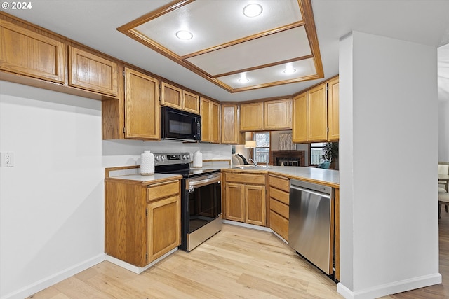 kitchen with kitchen peninsula, light wood-type flooring, sink, and stainless steel appliances