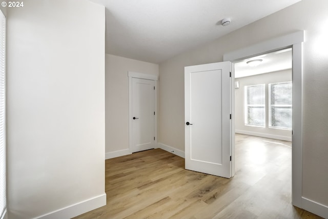 hallway featuring light wood-style flooring and baseboards