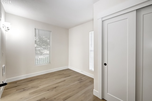 unfurnished bedroom with baseboards, wood finished floors, and a closet