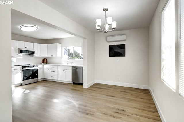 kitchen with light hardwood / wood-style flooring, white cabinets, hanging light fixtures, and stainless steel appliances