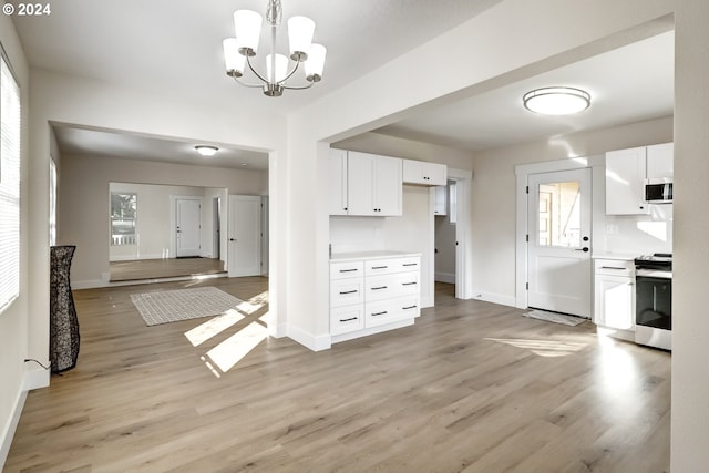 kitchen with a notable chandelier, decorative light fixtures, white cabinetry, appliances with stainless steel finishes, and light hardwood / wood-style floors