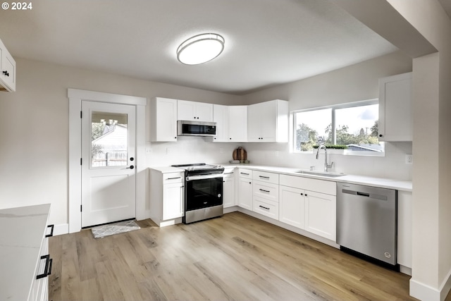 kitchen with a wealth of natural light, sink, white cabinetry, and stainless steel appliances