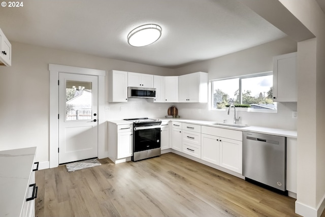 kitchen with stainless steel appliances, light wood-style flooring, a sink, and a wealth of natural light