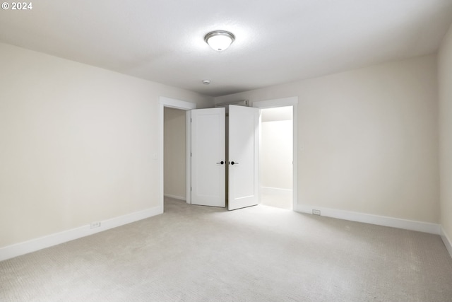 spare room featuring light carpet and baseboards