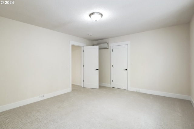 unfurnished bedroom featuring a wall mounted air conditioner and light carpet