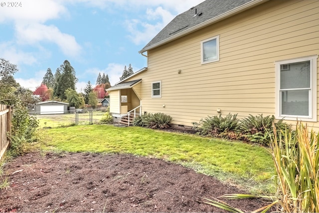 exterior space featuring roof with shingles, fence, and a yard