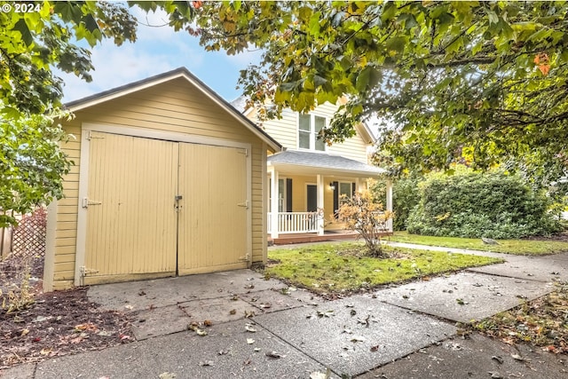 view of outbuilding with an outdoor structure, concrete driveway, and covered porch