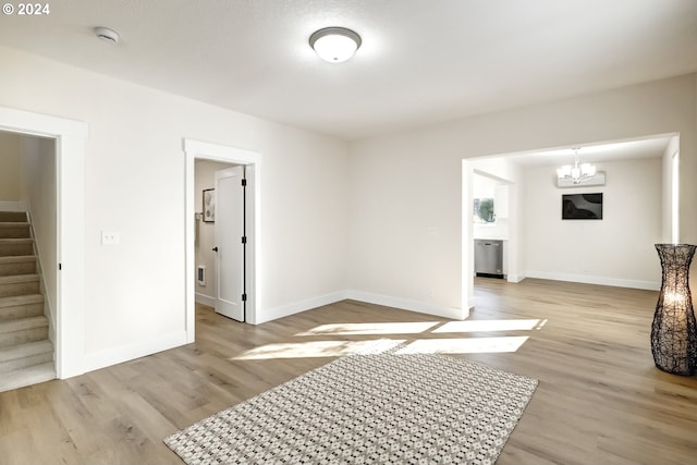 interior space with stairway, baseboards, light wood-type flooring, and an inviting chandelier
