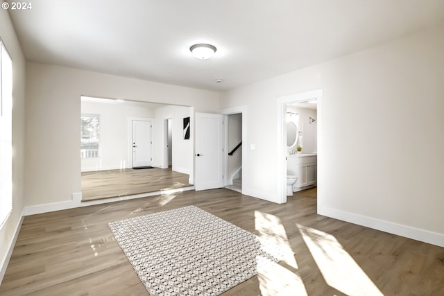 unfurnished bedroom featuring baseboards, connected bathroom, and light wood-style floors
