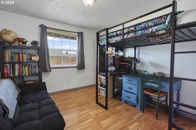 bedroom with light hardwood / wood-style flooring and a textured ceiling