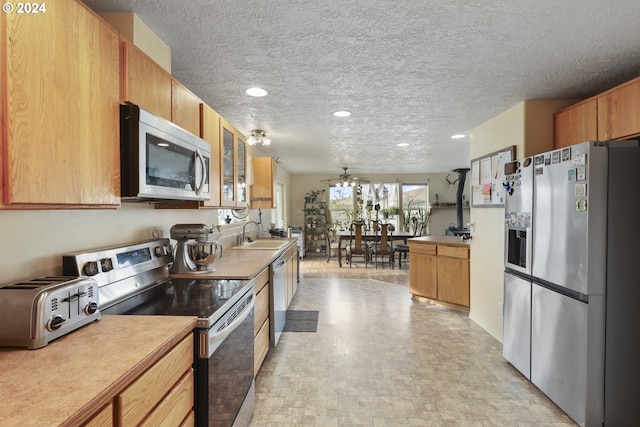 kitchen with appliances with stainless steel finishes, sink, a textured ceiling, and ceiling fan