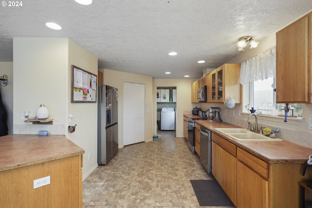 kitchen with sink, washer / dryer, stainless steel appliances, and a textured ceiling