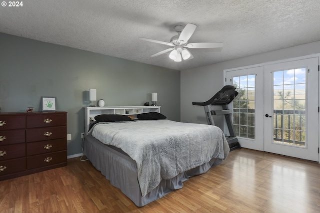 bedroom with wood-type flooring, access to exterior, a textured ceiling, and french doors