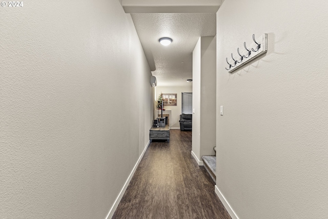 hallway with a textured ceiling and dark wood-type flooring