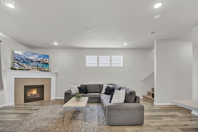 living room featuring a tiled fireplace and light hardwood / wood-style floors