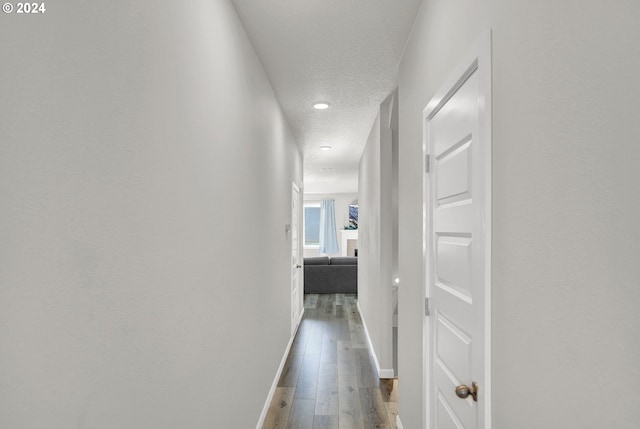 corridor with a textured ceiling and wood-type flooring