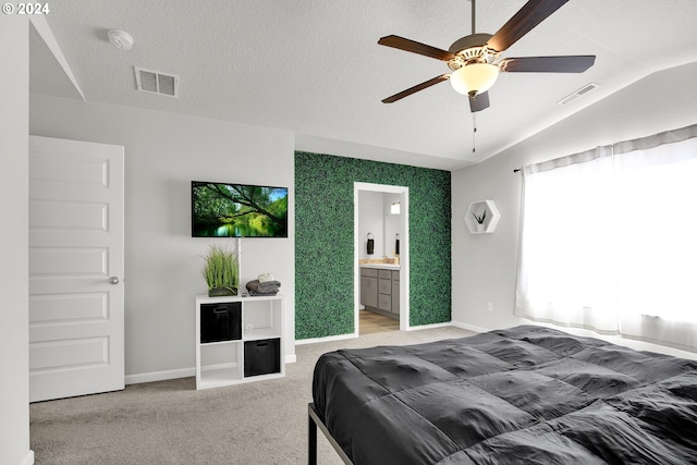 carpeted bedroom with ceiling fan, a textured ceiling, connected bathroom, and vaulted ceiling