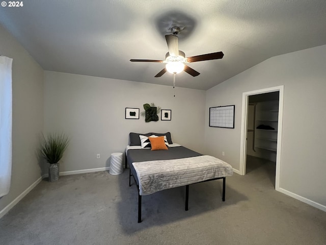 bedroom featuring light carpet, vaulted ceiling, a spacious closet, and ceiling fan