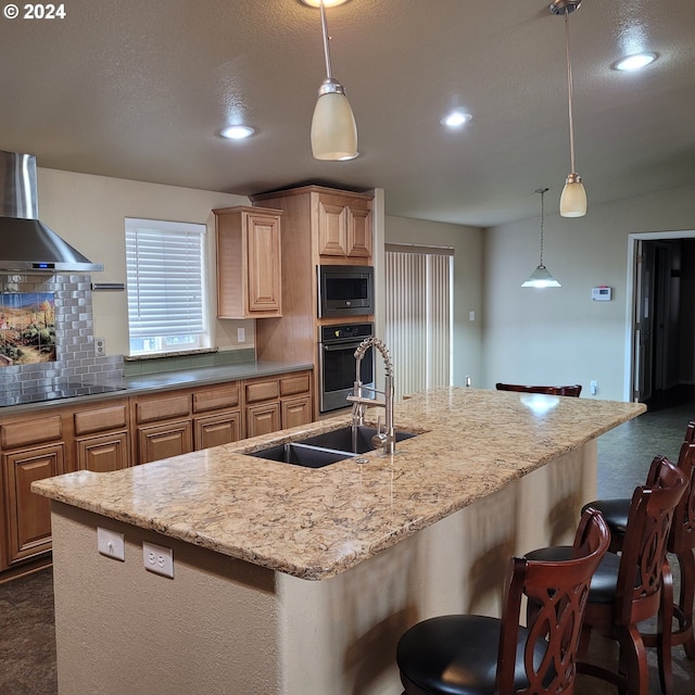 kitchen with a breakfast bar, light brown cabinetry, wall chimney exhaust hood, and stainless steel appliances