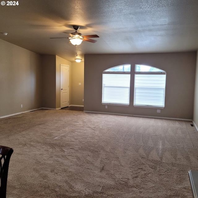 unfurnished room featuring ceiling fan, carpet floors, and a textured ceiling