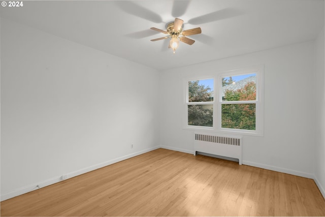 unfurnished room with ceiling fan, radiator heating unit, and light hardwood / wood-style flooring