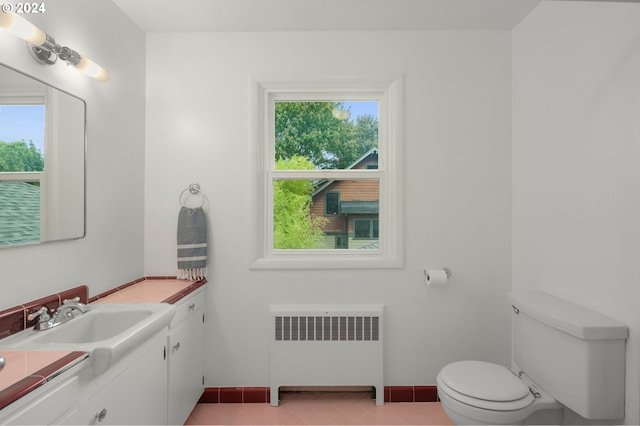 bathroom with toilet, vanity, plenty of natural light, and radiator heating unit